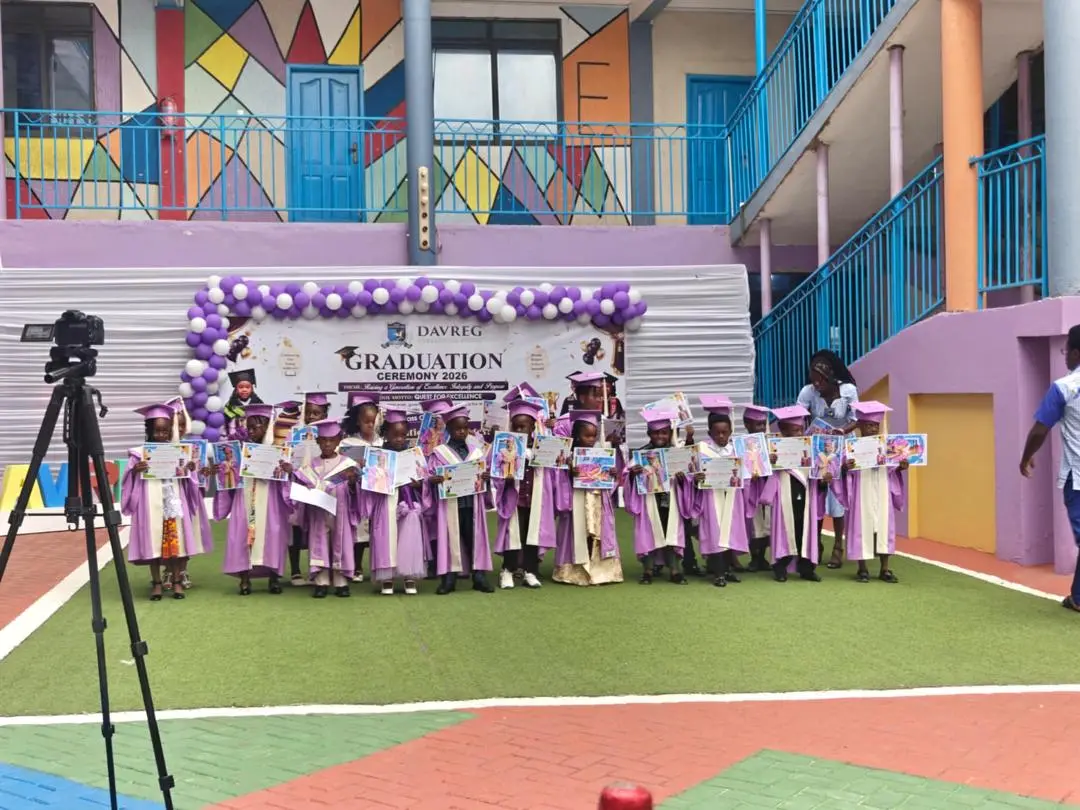 The DavReg Class of 2026 in purple graduation gowns, holding their certificates in front of the ceremony banner