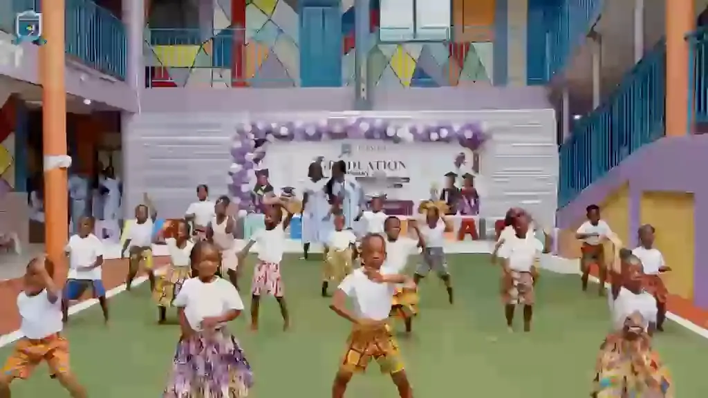 Pupils in white shirts and ankara skirts performing a cultural dance in the school courtyard
