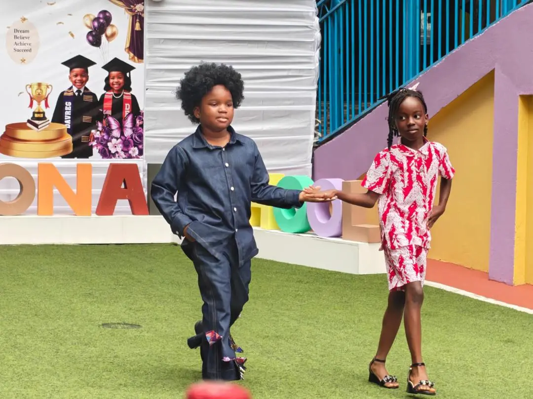Two pupils walking hand in hand during the graduation fashion parade