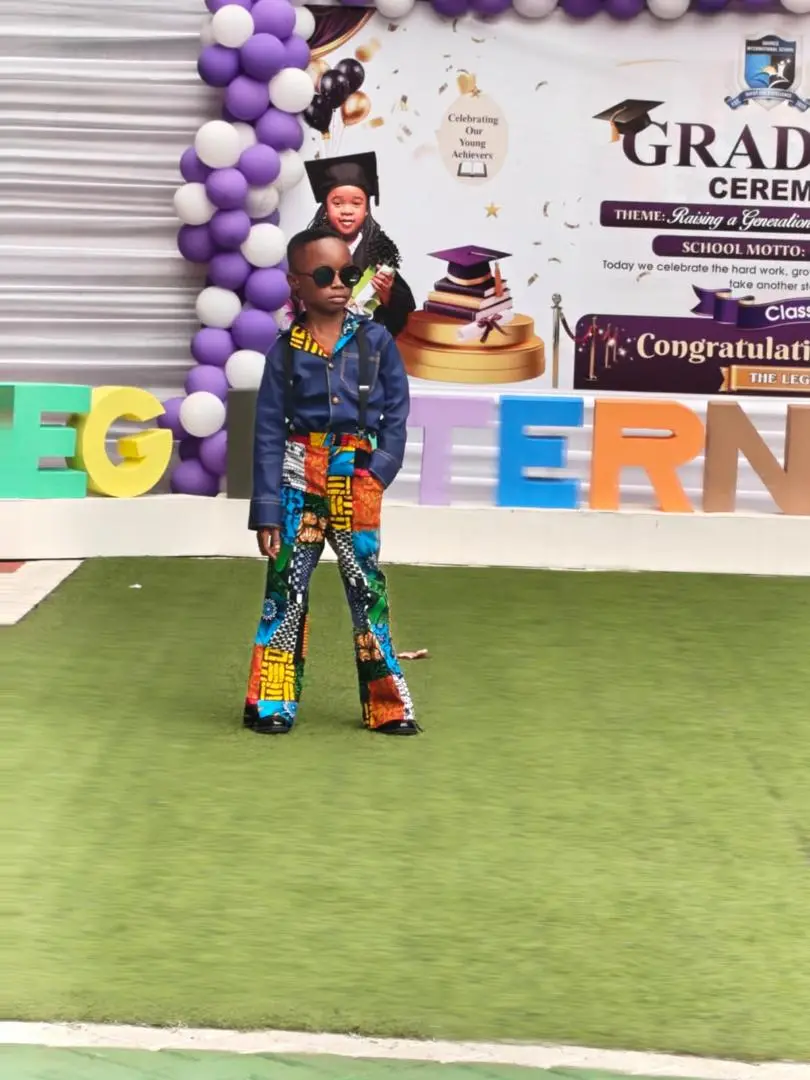 A pupil in sunglasses, a denim jacket and patchwork ankara trousers on the runway