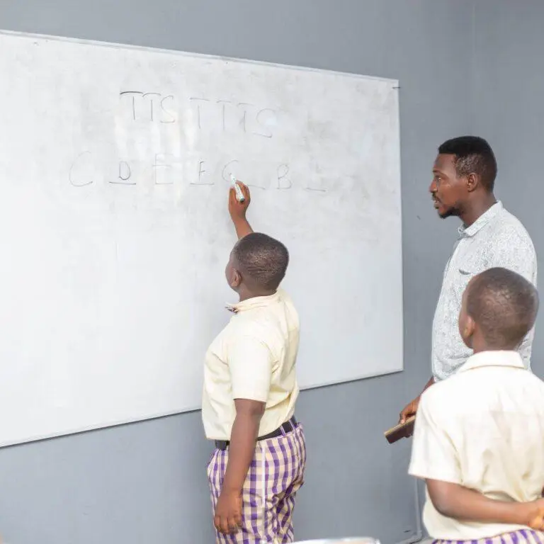 A teacher working at the whiteboard with two pupils